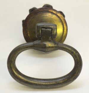 Close-up of a cast iron drop ring drawer pull with a patina finish and a visible mounting plate.