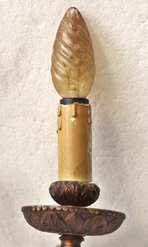 Close-up of a Victorian wall sconce with a bronze body and copper finish, showing the top candle-shaped light holder and the decorative carved cup beneath it.