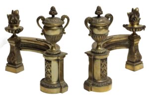 Pair of French bronze fireplace andirons with ornate curved supports and urn tops, one side showing a capped urn and the other a flame top urn.
