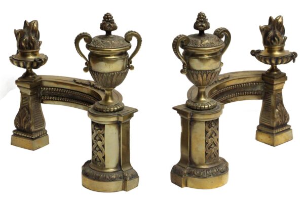 Pair of French bronze fireplace andirons with ornate curved supports and urn tops, one side showing a capped urn and the other a flame top urn.