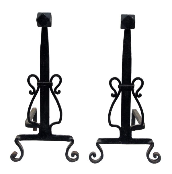 Pair of black wrought iron andirons with scrollwork sides and turned feet, shown as a matching pair.