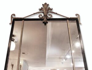 Vintage French wall mirror with a rectangular black frame and ornate gold fleur-de-lis embellishment at the top.