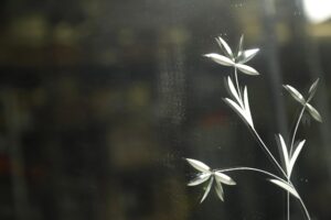 Vintage beveled and etched wall mirror with floral details, shown in close-up with a broken corner and chipping visible.