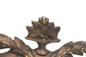 Close-up of an ornate bronze applique showing the urn top and leaf details in an antique bronze finish.