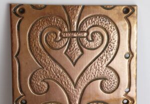 Ornate solid bronze wall plate with a rectangular shape, hammered detailing, and a decorative heart motif.