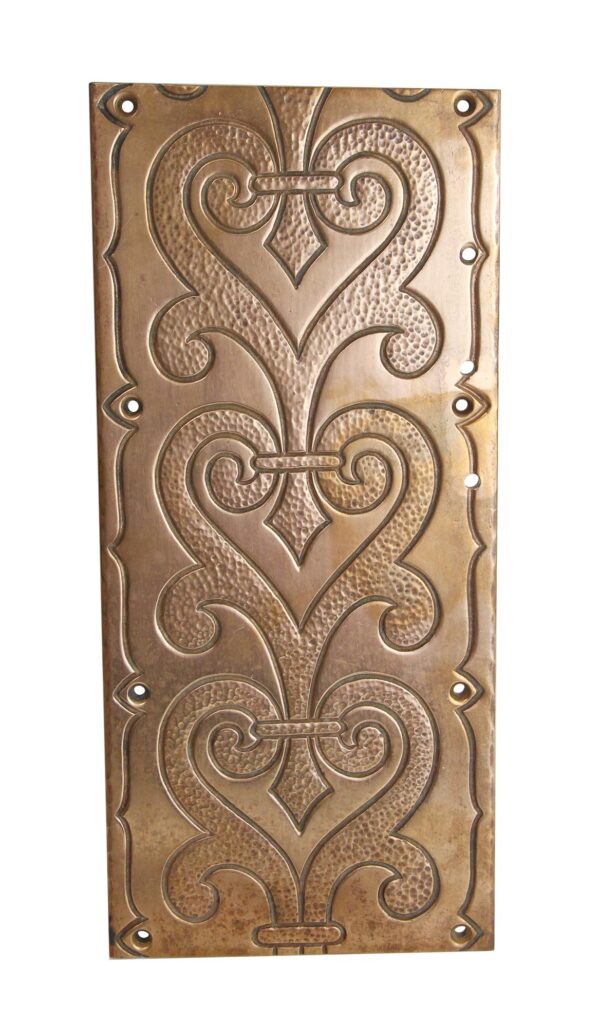 Ornate rectangular bronze wall plate with a decorative heart motif and hammered details, shown front on with mounting holes around the edges.