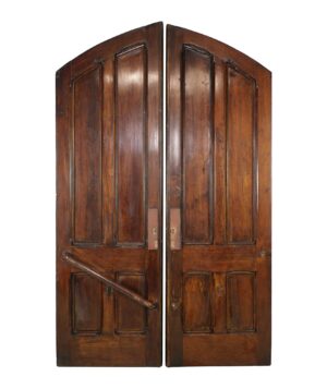 Antique wood church double doors with an arched top, four vertical panels, and a diagonal brace on one door, shown closed and in dark wood tone.
