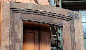 Single slanted arch door with two panels, shown in a close-up view with the glass missing and visible hardware at the top corner.