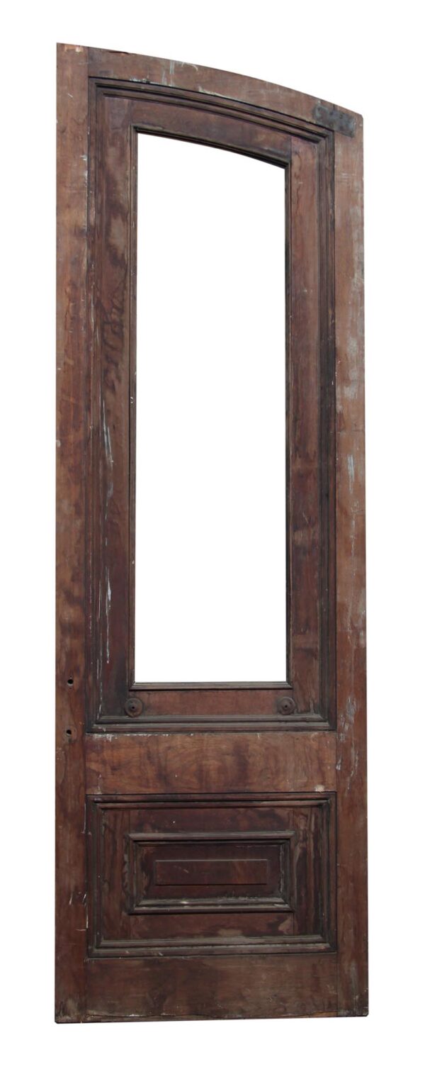 Single slanted arch door in dark wood tone with two panels and a large missing glass opening.