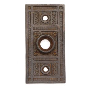 Ornate cast iron door back plate with three circular keyhole openings and a rectangular Aesthetic pattern.