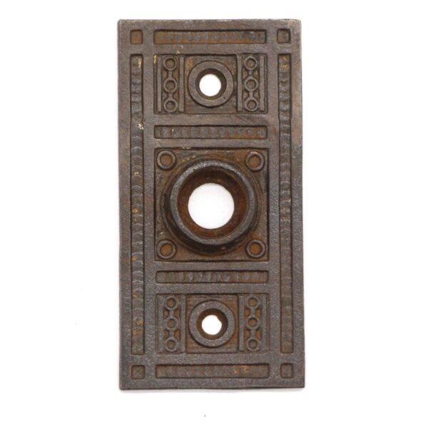 Ornate cast iron door back plate with three circular keyhole openings and a rectangular Aesthetic pattern.