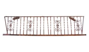 Rusted wrought iron fire escape balcony front with ornate scroll details and bent frame, shown in a straight-on view.