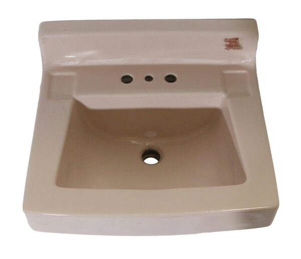Vintage pink porcelain sink with a rounded trapezoid bowl, three faucet holes, and a central drain opening shown from above.