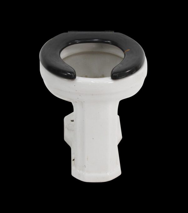 Art Deco toilet bowl with a black seat and white porcelain body, shown from above with visible wear.