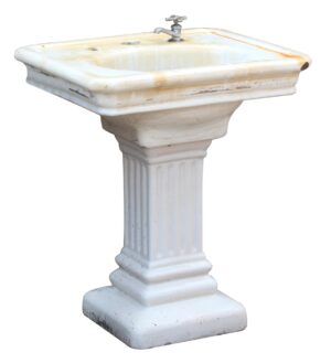 Pedestal sink with a fluted base and a single faucet hole, shown in white porcelain finish with visible chips and wear.