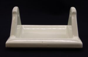 Ceramic flush mount toilet paper holder with a pale yellow porcelain finish, shown in a close-up front view with two side supports.