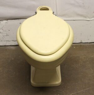 1950s light yellow toilet with matching lid and seat, shown from the front.