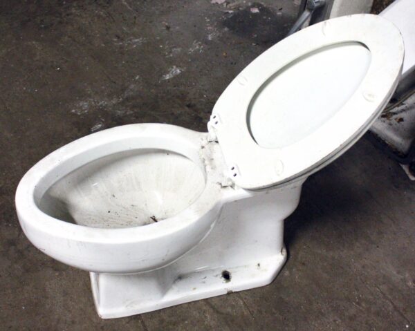 Vintage white toilet with the seat and lid open, shown in a side view.