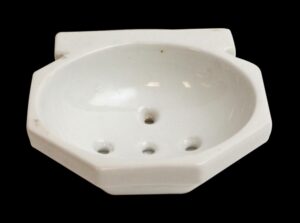 White ceramic wall-mounted sponge dish with a rounded basin and four mounting holes, shown in a top view with visible surface wear.