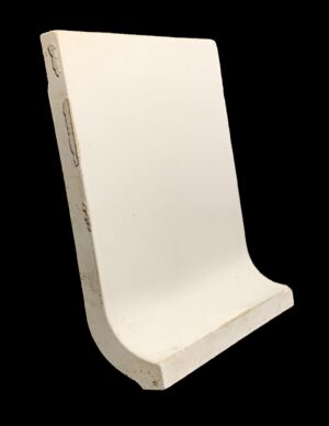 White ceramic baseboard tile with a curved profile and chipped edges.