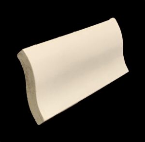 Off white S-shaped cap tile with a curved profile and smooth plain surface, shown with a rough chipped edge on one end.