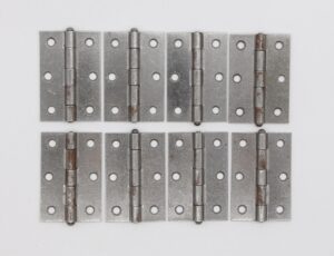 Set of eight steel butt cabinet hinges with five knuckles, rounded tips, and visible rust and age wear.