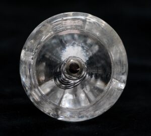 Round clear glass cabinet knob shown from the back, with a central mounting hole and faceted edge detail visible around the circular form.