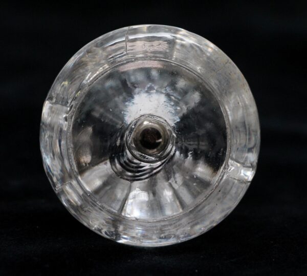 Round clear glass cabinet knob shown from the back, with a central mounting hole and faceted edge detail visible around the circular form.