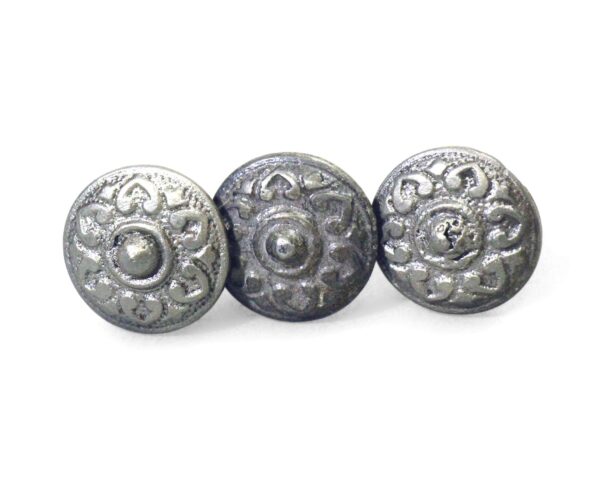 Three antique cast iron cabinet knobs with an eight-fold floral design and rounded centers, shown in a close-up view.