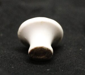 White round ceramic drawer knob shown in close-up, with the metal screw end visible and slight age wear on the surface.