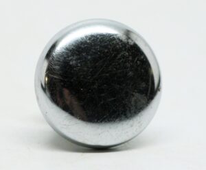 Close-up of a chrome cabinet knob with visible surface wear and scratches.