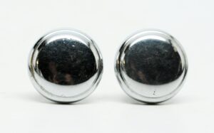 Pair of round chrome cabinet knobs shown side by side, with a reflective finish and visible wear.
