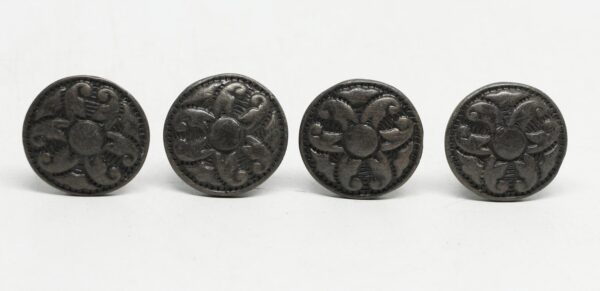Four round floral cabinet knobs with a Victorian-style raised pattern and black cast iron finish are shown in a row.
