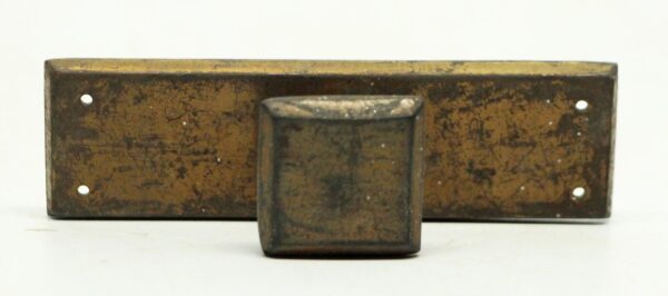 Square brass cabinet knob mounted on a rectangular plate with an antique finish and visible age wear, shown front on.