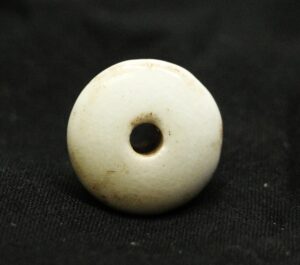 Round white ceramic drawer knob with a centered hole, shown in close-up against a dark background.