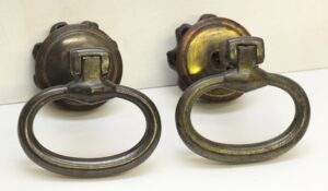 Pair of drop ring drawer pulls shown as a pair, with round backplates and oval rings in a traditional style.