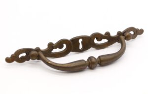 Pair of traditional brass drawer pulls with an antique finish, shown as a matching pair with curved handles and keyhole backplates.