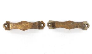 Pair of vintage brass bridge drawer pulls with an antique finish, shown side by side with visible mounting holes and surface wear.