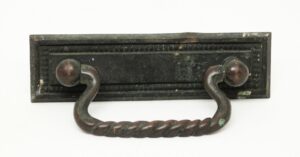 Traditional bronze bail drawer pull with a rectangular backplate and twisted handle, shown in a close-up view with some paint wear.