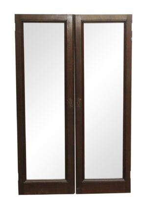 Pair of walnut framed cabinet doors with two tall glass panels and original hardware shown closed together.