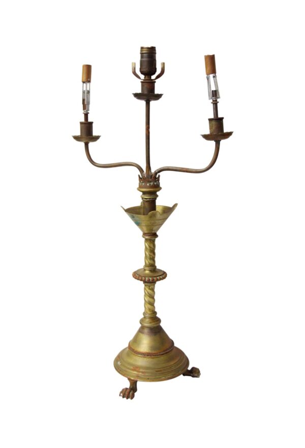 Three-light brass table lamp with a twisted stem, claw foot base, and candle covers on the sockets.