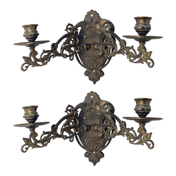 Pair of Art Nouveau brass piano candle sconces with ornate wall plates and adjustable arms, shown as a pair.