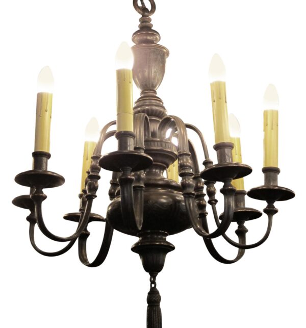 Georgian style bronze eight-arm chandelier shown in a front view with candle-shaped bulbs and an elongated bottom finial.