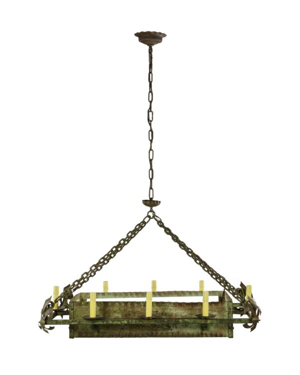 Rectangular wrought iron chandelier with verdigris patina, eight candle-style sockets, and hanging chain support.