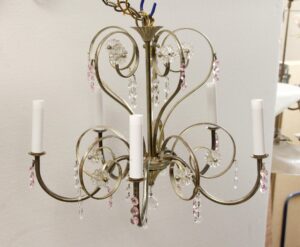 Silver-plated chandelier with five curved arms, clear glass florets, and pink crystal drops, shown with candle-style sleeves.