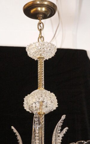 Clear glass chandelier hanging from a brass chain, showing the upper rostrato bowl and twisted center stem.
