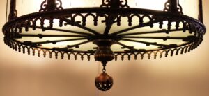 Art Deco chandelier with an open-work bronze frame and frosted glass panels, shown from below with a central stem and spherical finial.