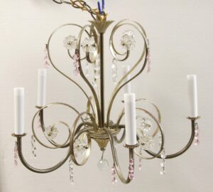French chandelier with five curved arms, white candle sleeves, and clear floret details, finished with hanging pink crystal bead strands and faceted pendants.