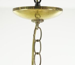 Close-up of the chandelier’s antique brass canopy and chain-link suspension with clear beveled glass panels visible below.
