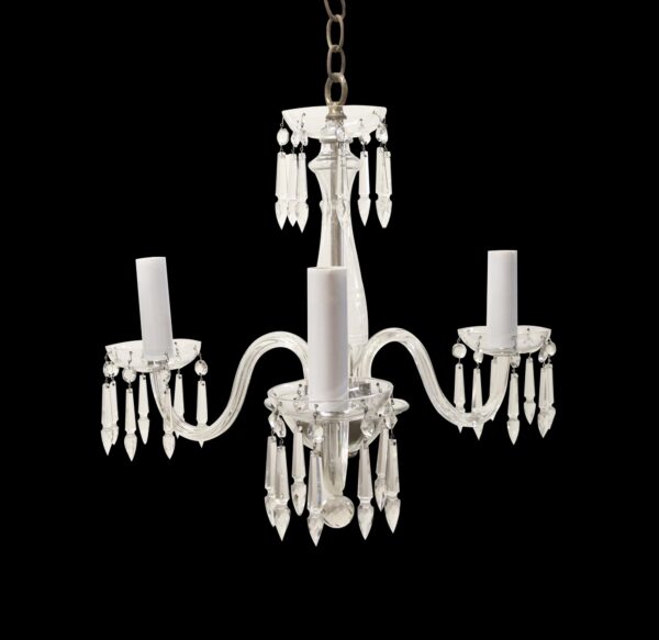 Clear crystal three-arm chandelier with a fluted center stem, faceted prisms, and candle-style sockets on each arm.